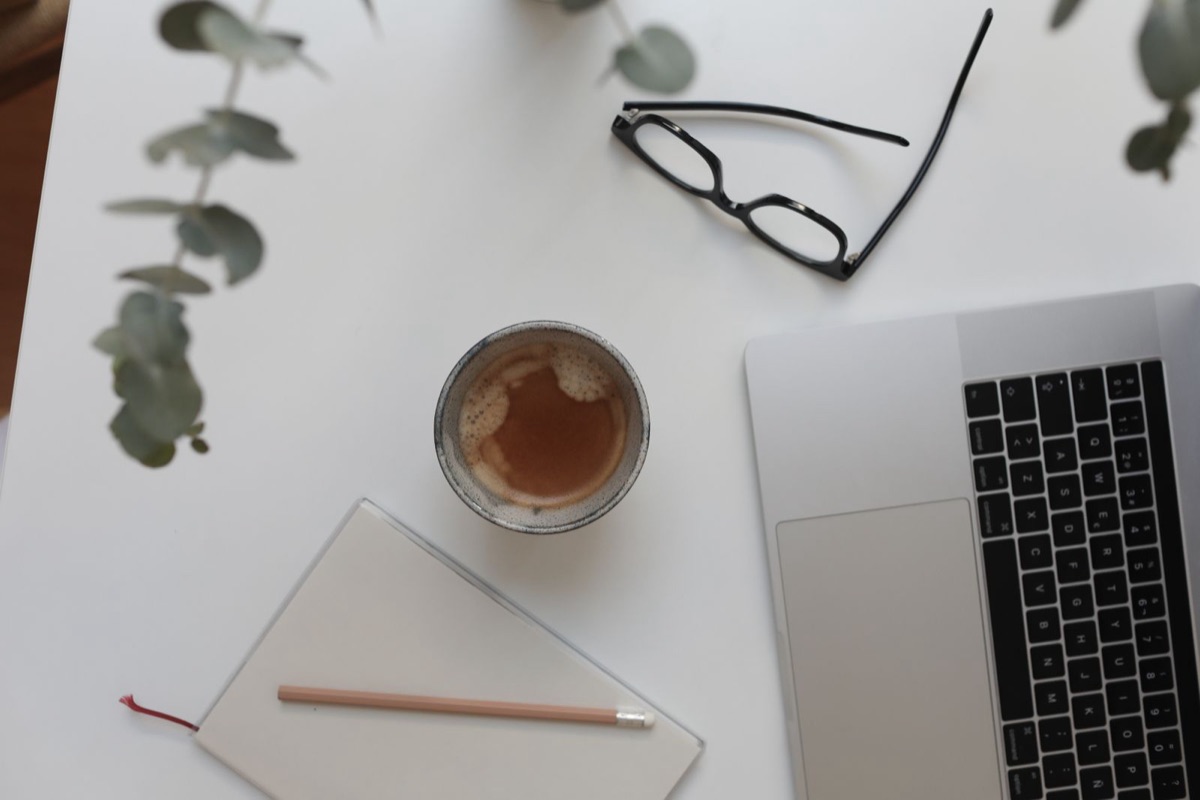 Pracovní stůl s notebookem, kávou a zápisníkem — plánování webu pro živnostníka